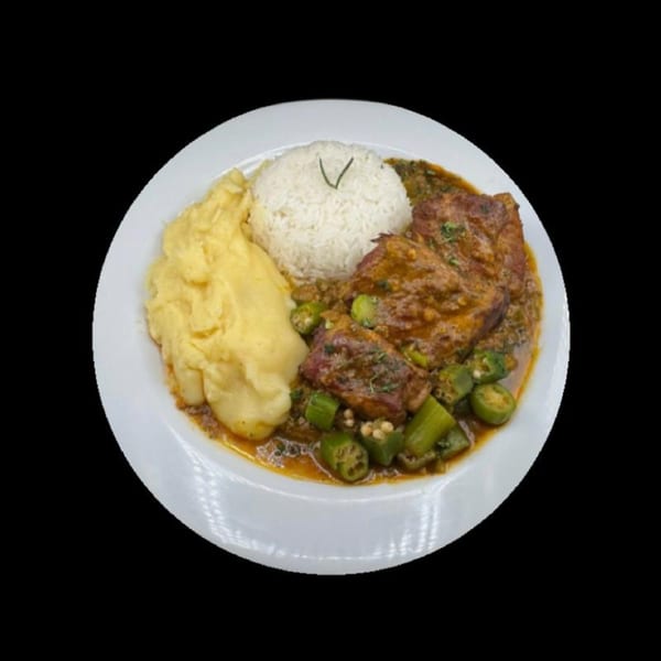 A plate of stewed meat with okra, white rice, and a side of fufu.