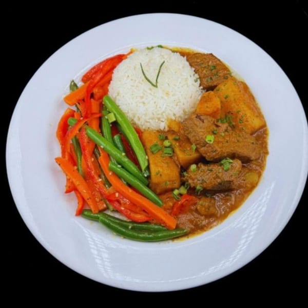 A white plate with rice, beef stew, green beans, and red bell peppers.